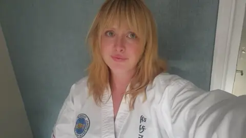 Supplied A selfie of Kirsty Harrison, who has shoulder-length strawberry blonde hair in a fringe. She is wearing white Taekwando robes.