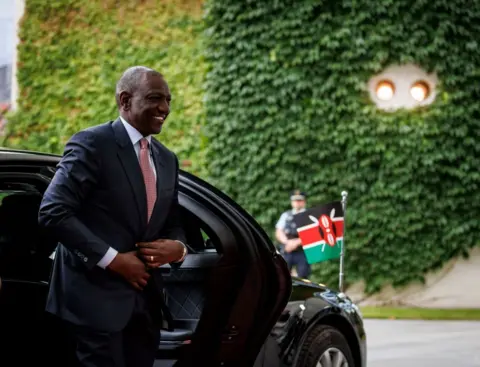 AFP William Ruto strides out of an official diplomatic car, which has a small Kenyan flag on its bonnet.