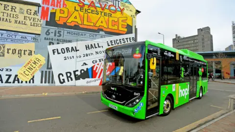Leicester City Council A small green bus in front of a colourful mural