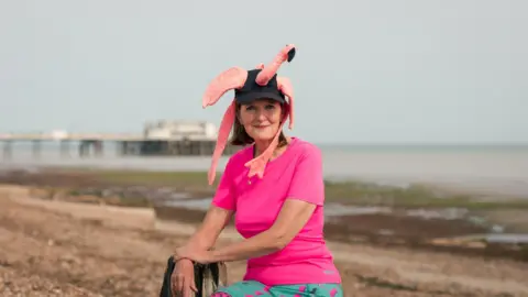 A woman in a pink outfit. She has a flamingo hat on. 