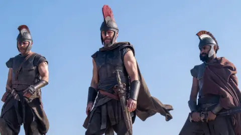 (L-R) Jimmy Gonzales as Cepheus, Matt Damon as Odysseus and Himesh Patel as Eurylochus in their warrior outfits, armoury and swords 