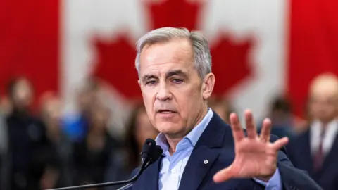 Mark Carney in front of a Canadian flag