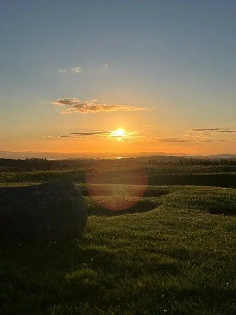 Lorna O'Connor A sunrise taken from the top of a hill. The sky is yellow and orange and there is grass over the hill.