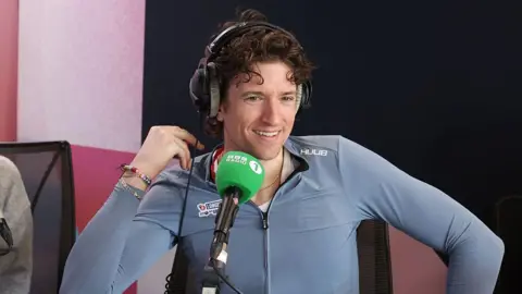 Getty Images Greg James at a Radio 1 interview after he crosses the finish line during the Radio 1 Longest Ride challenge for Comic Relief at Murrayfield Stadium on March 20, 2026 in Edinburgh, Scotland. BBC Radio 1 presenter Greg James took on a 100km-a-day tandem cycling challenge across the UK for Comic Relief, riding for eight days from Weymouth to the finish line in Edinburgh