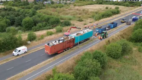 Drone shot of trailers dumped on road being emptied