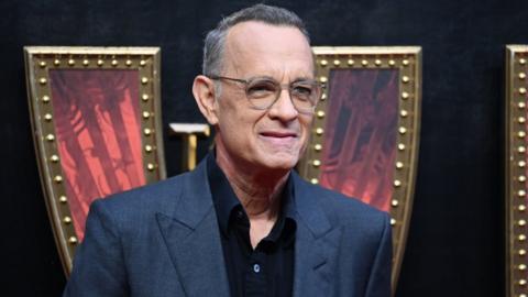 Tom Hanks shouts at fans after causing wife to trip - BBC News