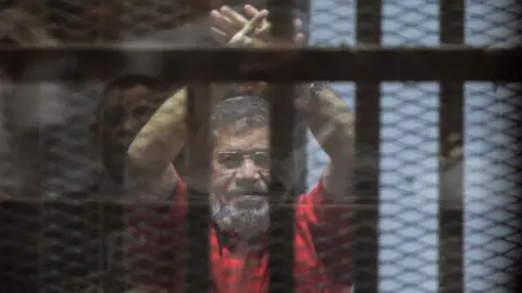 EPA Former Egyptian President Mohamed Morsi raises his hands during a court appearance