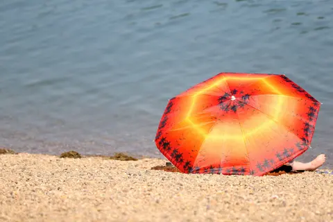 EPA A woman rests under a parasol at the Ada lake in Belgrade, Serbia