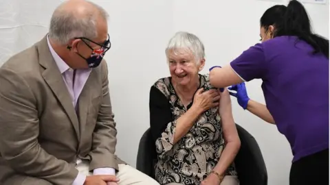 EPA Woman receiving vaccine jab sitting next to Scott Morrison