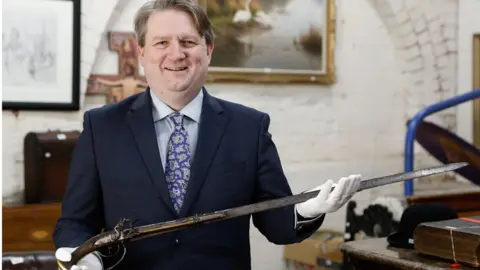 PA Media Bloomfield Auctions Managing Director Karl Bennett with a sword pistol linked to the 1689 Siege of Derry