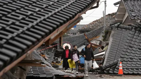 Reuters Three people walking through a town in Japan devastated by a tsunami