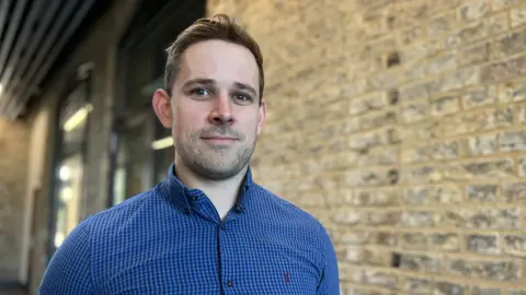 Emma Baugh/BBC News Man next to a wall