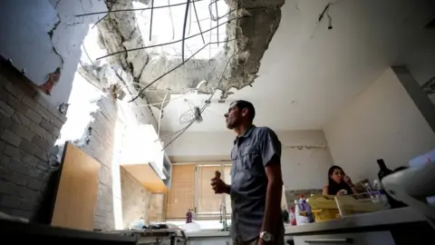 Reuters Adi Vaizel, looks at the damage caused to the kitchen of his house after it was hit by a rocket launched from the Gaza Strip