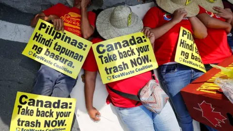 EPA Demonstrators hold placards while lying down during a protest at the Canadian Embassy in the Philippines