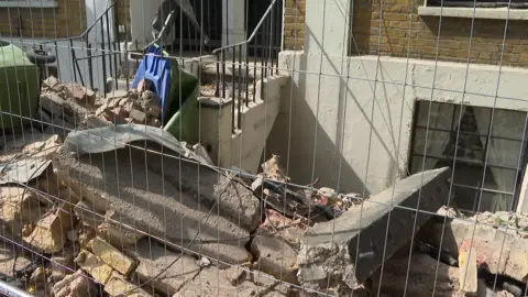 Piles of rubble and broken masonry outside one of the affected properties on Woodland Terrace in Charlton, with fencing installed around the site following the partial collapse.