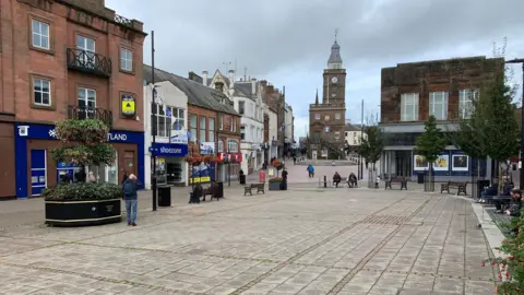 A modern view of Dumfries town centre with its distinctive sandstone Midsteeple in the distance
