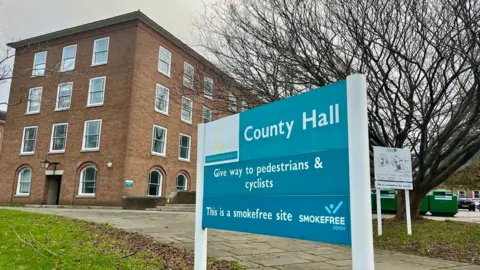 A sign for County Hall in front of the four-storey blocl of offices at County Hall