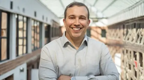 HubSpot Smiling Kipp Bodnar and with his arms folded, Kipp Bodnar wears a grey shirt.