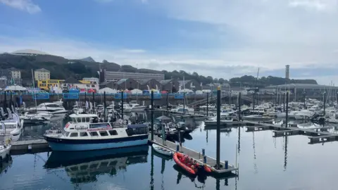 A marina full of a variety of boats in Jersey including yachts and emergency vessels. 