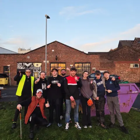 A group of men and and one woman with their thumbs up