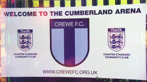 A sign saying Welcome to the Cumberland Arena and Crewe FC's badge