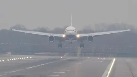 A plane lands in misty conditions from London Gatwick airport in Crawley, West Sussex. 