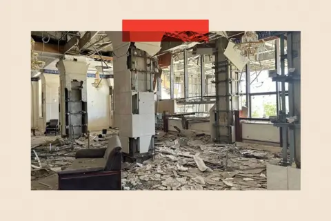 A room with shattered windows and smashed plaster covering the floors