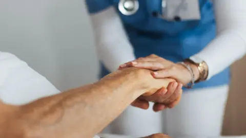 Getty Images A nurse holding the hand of a patient.
