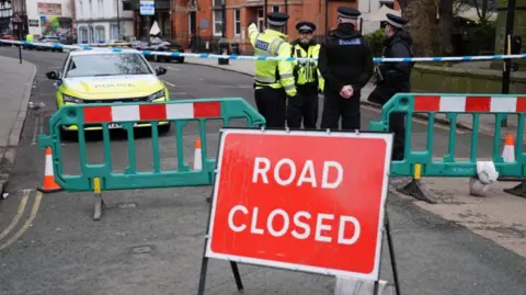 Jacob King/PA Wire Police officers standing near a cordon and road closed sign in Friar Gate, Derby, on Sunday 29 March 2026.