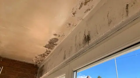 The porch at the home. The ceiling and upper walla is covered in dark patches