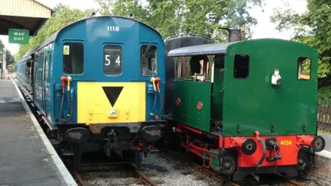 Lavender Line Preservation Society Two engines at Isfield Station - a green steam one and a blue diesel one.