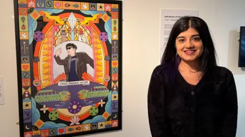 Provided Sofia Barton standing next to a similarly colourful design, this time depicting local artist Craig Puranen Wilson.
