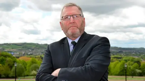 Pacemaker Doug Beattie standing with arms folded outside Stormont