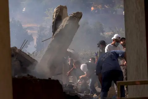 Darren Conway / BBC Samir and his crew search for bodies in the rubble.