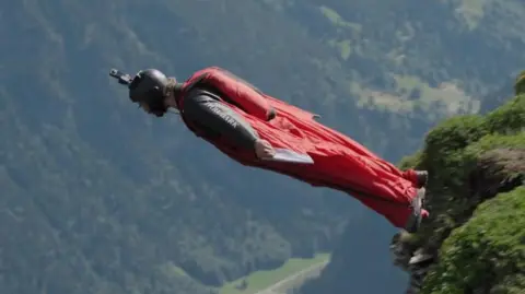 BBC Man in wing suit flying through the sky. Picture taken from 2024 BBC Scotland documentary