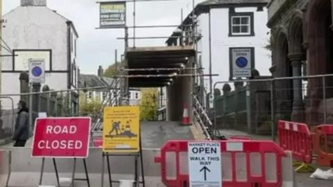 Bridge entry barricaded off with signs saying 'road closed'