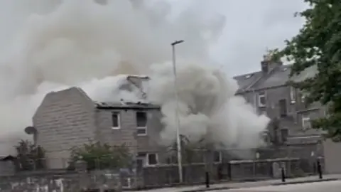 Smoke billowing from a house on fire.