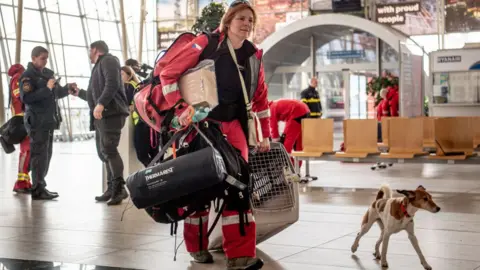 Getty Images A female firefighter and her rescue dog arriving at a Turkish airport