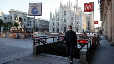 Reuters A man wearing a protective face mask walk next to a near-empty Duomo square in Milan