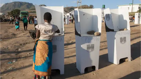 Getty Images A woman casts her vote at the Ndirande Community ground polling centre on May 21, 2019 in Blantyre, southern Malawi, during the country general Elections. - Millions of voters in Malawi cast ballots today in a closely-fought election, with incumbent President battling to hold off two rivals in a race that focused on corruption allegations and economic development.