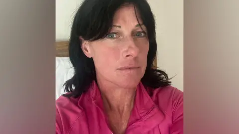 Lucy Conroy Woman with long dark hair wearing pink top