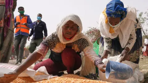 Getty Images Woman scooping up lentils during an aid operation in Mekelle