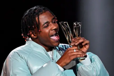 BERTRAND GUAY/AFP French-Cameroonian singer Yamê holds his Best Male Newcomer award.