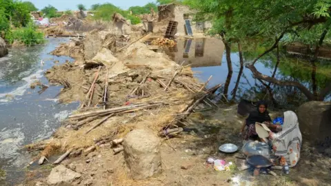 Getty Images Flood affected women make bread for their family beside damaged mud houses after heavy monsoon rains in Jaffarabad district, Balochistan province, on August 28, 2022.