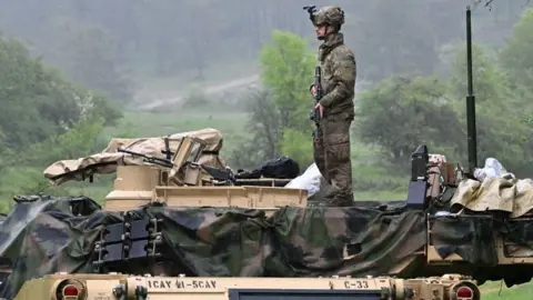 CHRISTOF STACHE/AFP A US soldier stands on a US Army M1A2 Abrams tank during the Combined Resolve 18 exercise at the Hohenfels trainings area, southern Germany, on May 11, 2023