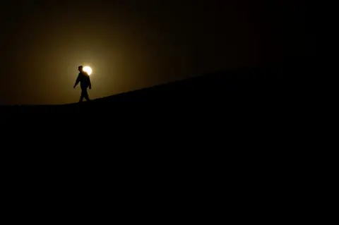 BORJA SUAREZ/REUTERS A soldier from the Sahrawi Popular Liberation Army walks along a dune.