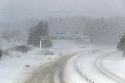 PA A police car in the snow on the M876 to Glasgow