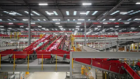 Peter Byrne/PA Media A royal mail sorting office, with belts full of parcels