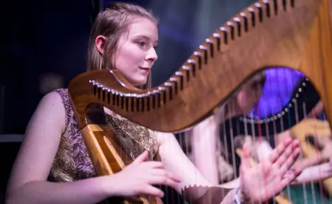 CBoI A young woman plays a harp as part of the orchestra