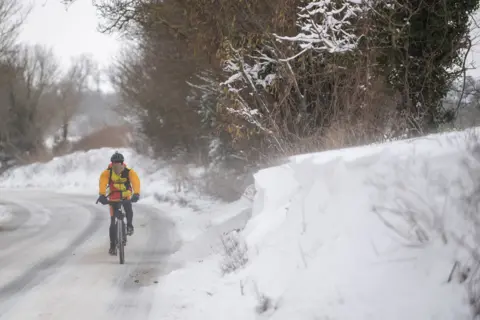 PA Media A cyclist makes their way through snow in Barham, near Ipswich, on 8 February 2021